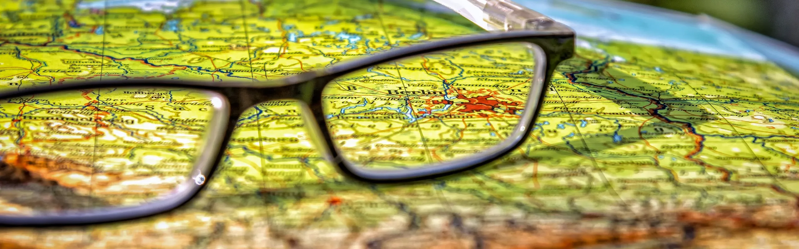 Foto mit Landkarte, darauf liegt eine schwarze Brille