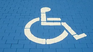 Weißes Rollstuhl-Logo auf hellblauem Grund