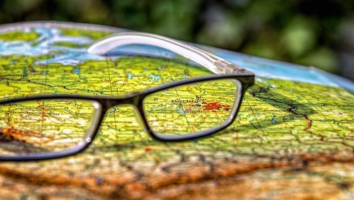 Foto mit Landkarte, darauf liegt eine schwarze Brille