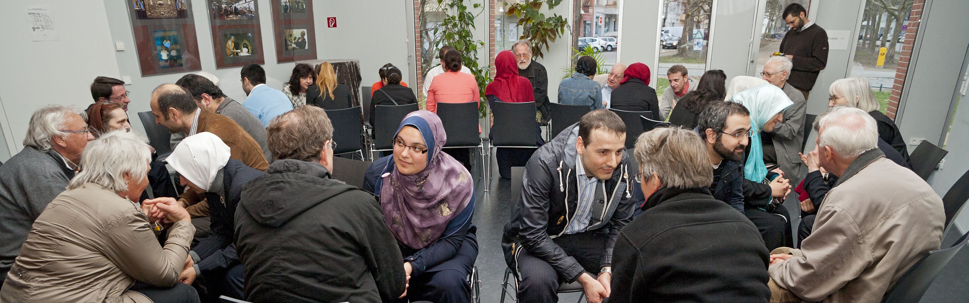 Menschen unterschiedlicher Kulturen im Zweier-Gespräch sitzend