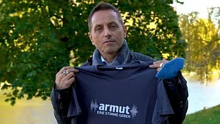 Thomas de Vachroi mit T-Shirt, darauf Logo "armut eine stimme geben"