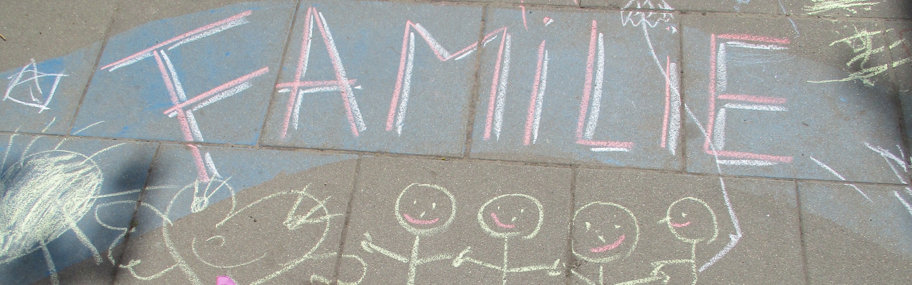 Kreidezeichnung mit Text 'Familie' auf dem Bürgersteig