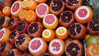 Halbierte Granatäpfel, Orangen und Grapefruits liegen dicht beieinander auf einem Marktstand
