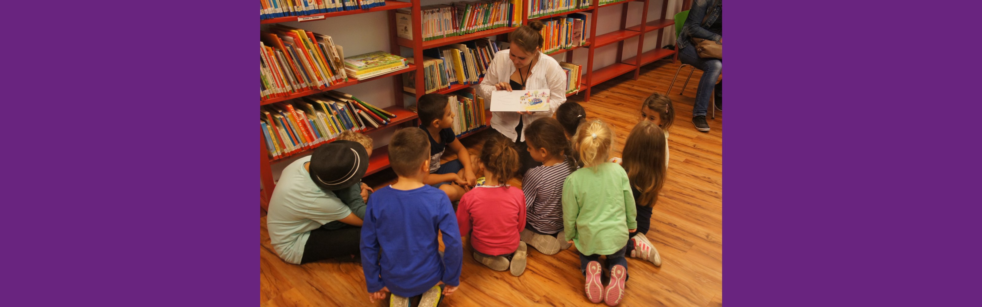 Kinder sitzen auf dem Boden vor einer Pädagogin