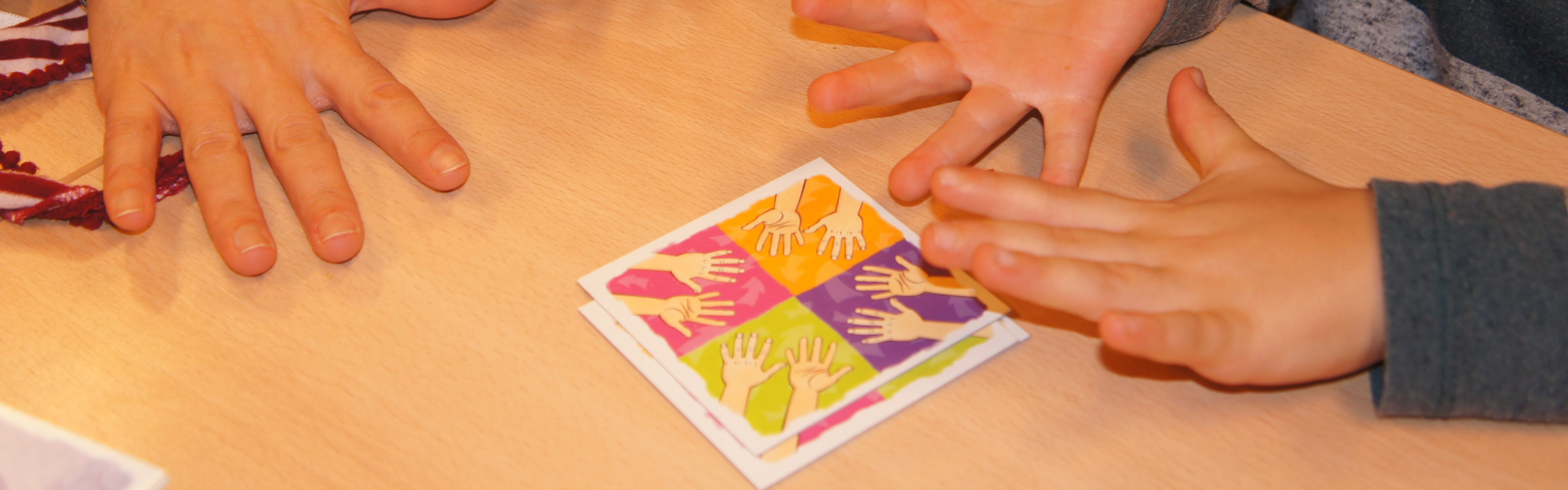 Spielkarten auf einem Tisch mit Kinderhänden
