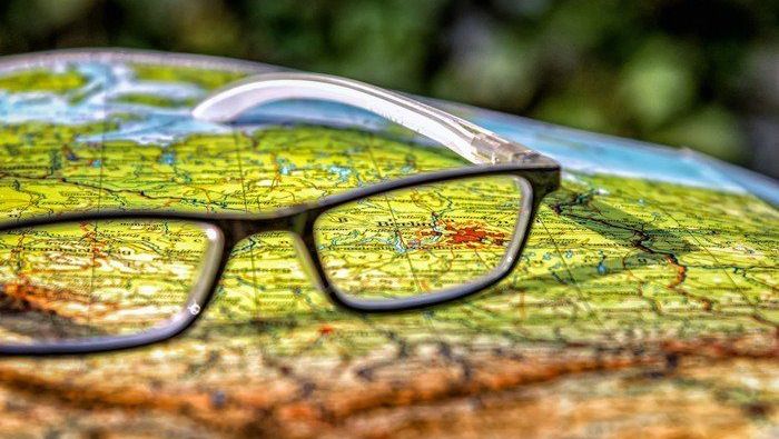 Foto mit Landkarte, darauf liegt eine schwarze Brille