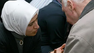 Frau mit weißem Kopftuch spricht mit Mann