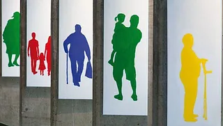 Verschiedene Menschen dargestellt als einfarbige Shilouetten: Mensch mit Krücken in gelb, Familie in rot, Vater mit Kind in grün