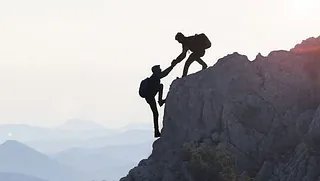 Zwei Bergsteiger, die sich beim Aufstieg helfen